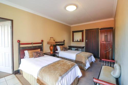 a hotel room with two beds and a chair at North Hill Guesthouse in Bloemfontein