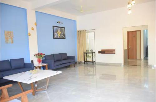 a living room with blue couches and a table at Kunal Luxury Hotel in Manāli