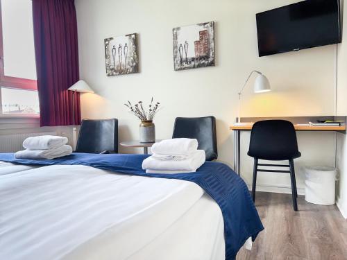 a bedroom with a bed and a desk with chairs at Hotel Frederikshavn in Frederikshavn