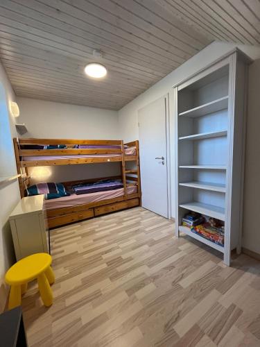 a bedroom with two bunk beds and a yellow stool at Ferienhaus 'Welle und Watt' - 2024 neu renoviert in Friedrichskoog-Spitz