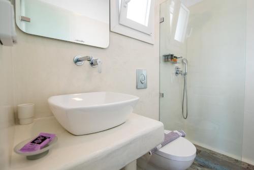 a white bathroom with a sink and a shower at Depis private villas Plaka Naxos in Plaka