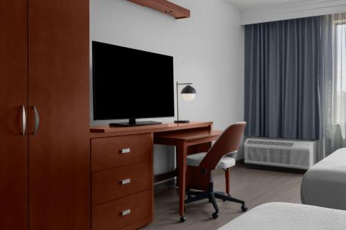 a hotel room with a desk with a television on it at Courtyard By Marriott Houston Kingwood in Kingwood