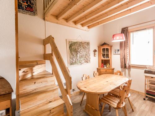 une salle à manger avec une table en bois et des escaliers dans l'établissement Duplex cosy 6 pers à 150m des pistes avec parking gratuit, balcon, appareils à raclette et fondue - FR-1-329-86, à La Plagne Tarentaise