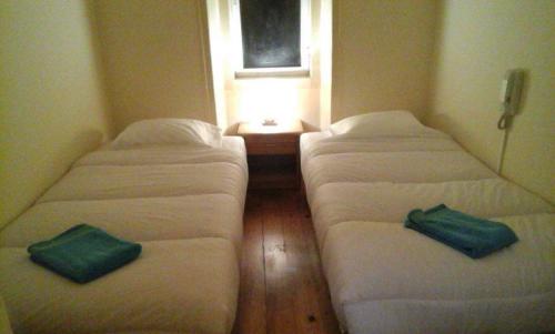 three beds in a room with a window at LisBangla Guest House in Lisbon