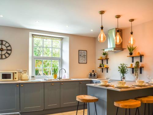 a kitchen with gray cabinets and a counter with stools at Yorkshire Cottage in Clayton West