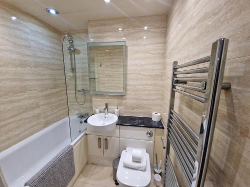 a bathroom with a toilet and a sink and a shower at Spacious 4Bedroom Home Sleeps 7 with 2 Full Baths in Gateshead