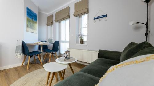 a living room with a green couch and a table at Haus Seeblick mit 9 Wohnungen in Alt Reddevitz