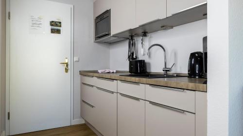 a kitchen with white cabinets and a sink at Haus Seeblick mit 9 Wohnungen in Alt Reddevitz