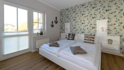 a bedroom with a white bed with a bird wallpaper at Haus Seeblick mit 9 Wohnungen in Alt Reddevitz