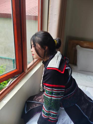 a woman is looking out of a window at SAPA HUB hostel in Sa Pa