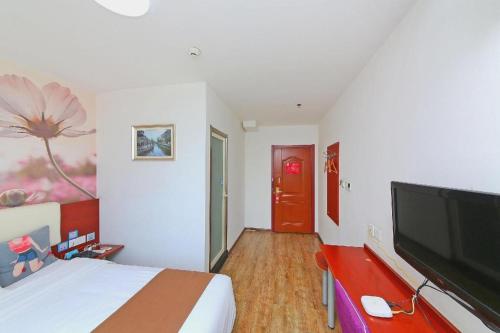 a bedroom with a bed and a flat screen tv at PAI Hotels·Shijiazhuang Development Zone Tianshan Science and Technology Park in Shijiazhuang