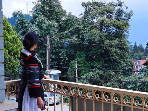 a woman standing on a balcony looking at trees at SAPA HUB hostel in Sa Pa