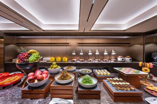 a buffet line with bowls of fruits and vegetables at Orange Crystal Qingdao May Fourth Square Olympic Sailing Center Hotel in Qingdao