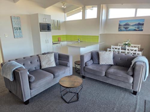a living room with two couches and a kitchen at Little Haven in Taupo
