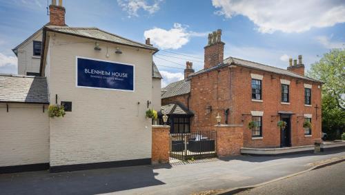 a building with a blue sign on the side of it at OYO Blenheim House in Etwall