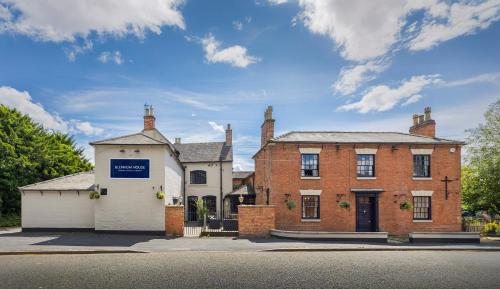 an old brick house with a blue sign on it at OYO Blenheim House in Etwall