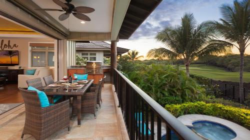 a balcony with a table and chairs and a hot tub at HOUSE OF JOY Light and Airy 4BR KaMilo Home with Heated Pool and Spa in Waikoloa