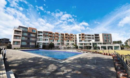 a large apartment building with a large swimming pool at Villa de Aewol in Jeju