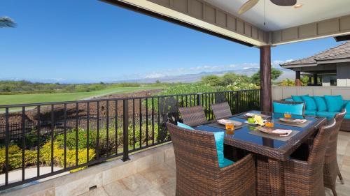 a patio with a table and chairs on a balcony at HOUSE OF JOY Light and Airy 4BR KaMilo Home with Heated Pool and Spa in Waikoloa