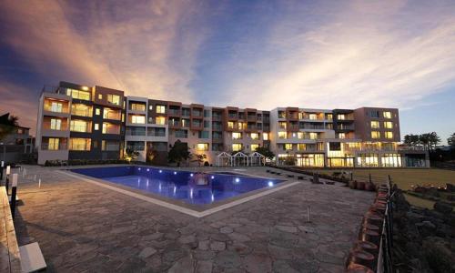 a large building with a swimming pool in front of it at Villa de Aewol in Jeju