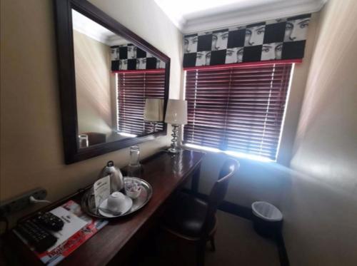 a desk with a mirror and a chair in a room at North Hill Guesthouse in Bloemfontein