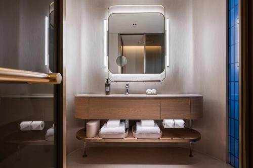 a bathroom with a sink and a mirror at Orange Crystal Qingdao May Fourth Square Olympic Sailing Center Hotel in Qingdao