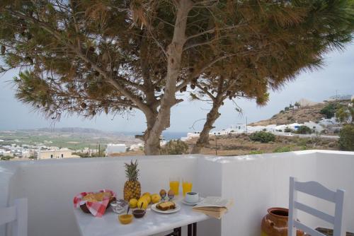 a table with fruit and juice on a balcony with a tree at Villa Galinia in Akrotiri