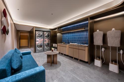 a living room with a blue couch and washing machines at Orange Crystal Qingdao May Fourth Square Olympic Sailing Center Hotel in Qingdao