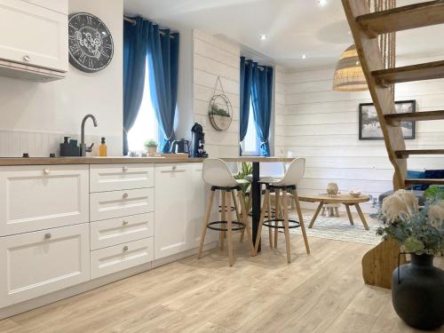 una cucina con mobili bianchi e un tavolo con sedie di Duplex climatisé avec Espace Cinéma a Riom