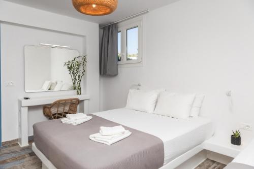a white bedroom with a bed and a mirror at Depis private villas Plaka Naxos in Plaka