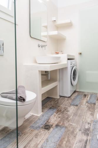 a bathroom with a toilet sink and a washing machine at Depis private villas Plaka Naxos in Plaka