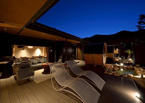 a deck with two chairs and a couch on a patio at 汐汲浜シーサイドヴィラ浜つづり in Miyazu