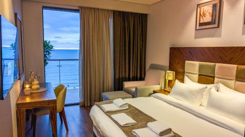 a hotel room with a bed and a desk and a window at Luxury Dreamland Oasis Apartments in Chakvi