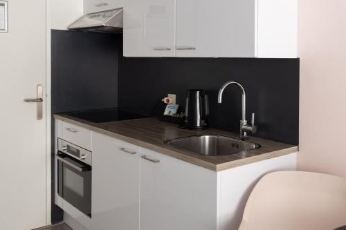a kitchen with white cabinets and a sink at Hotel2Stay in Amsterdam