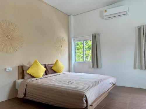 een slaapkamer met een groot bed met gele kussens bij Oh Town Villa in Thongsala