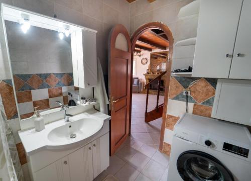a bathroom with a sink and a washing machine at Popolaros Traditional House in Zakynthos