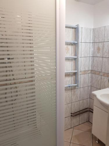 eine Glasduschtür in einem Badezimmer mit Waschbecken in der Unterkunft Entre Terre et Mer La Bichette in Guisy