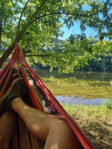 a person laying in a hammock overlooking a river at Péchaud in Lalinde