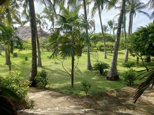 a garden with palm trees and a path at Sunny garden rooms Watamu in Watamu