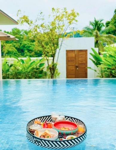 ein Tablett mit Essen auf dem Pool in der Unterkunft Lespalm Taraburi Pool Villa SHA Plus in Thalang