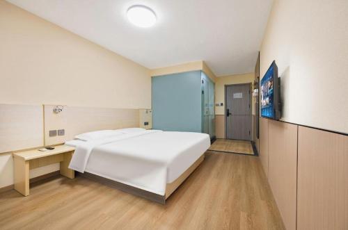 a bedroom with a large white bed and a desk at 7 Days Inn Baoding Railway Station in Baoding