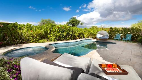 a swimming pool with chairs and a table next to it at SEA GLASS Stunning 3BR KaMilo Home with Heated Pool and Best View in Waikoloa
