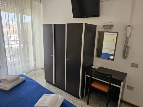 a bedroom with a bed and a desk and a mirror at Hotel Riviera Nuova Gestione in Cattolica