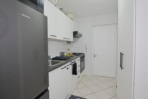 a white kitchen with a sink and a stove at SeeHUYS Boutique Bloubergstrand Beachfront Studio in Cape Town