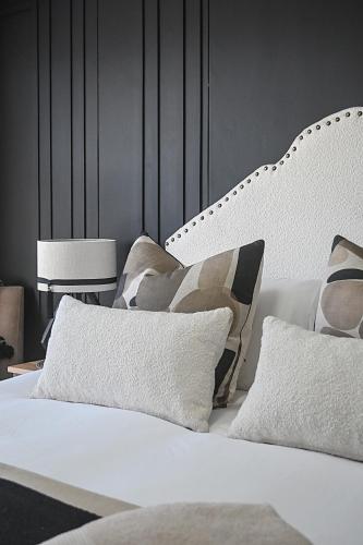 a bedroom with a white bed with pillows at SeeHUYS Boutique Bloubergstrand Beachfront Studio in Cape Town