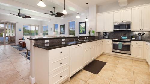 a kitchen with white cabinets and black counter tops at SEASHELL VILLA Lovely 3BR Kulalani Home with Private Beach Club Bikes in Waikoloa