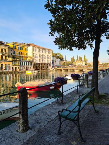 a bench sitting next to a canal with a boat at Palazzo Ai Capitani in Peschiera del Garda