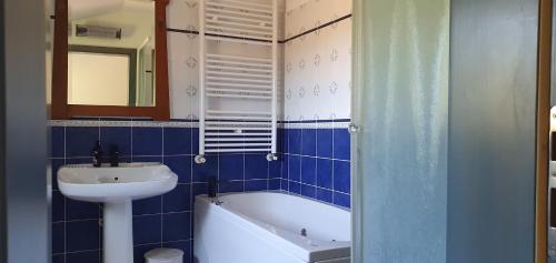 a blue tiled bathroom with a sink and a bath tub at Karsolina in Štanjel