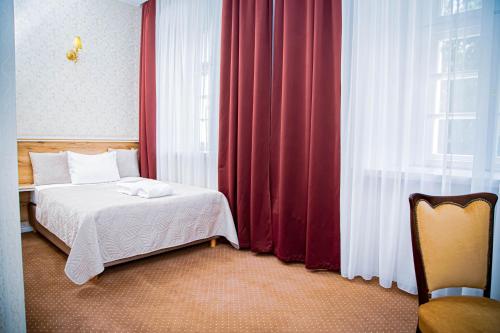 a bedroom with a bed and a window with red curtains at Hotel Nysa in Nysa