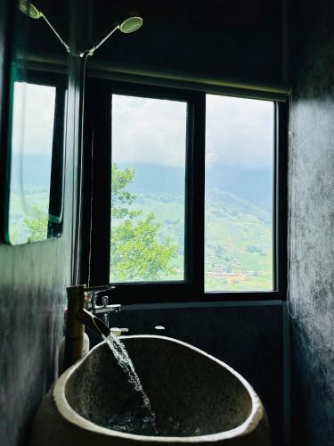 a bathroom with a sink with water coming out of a window at Dinh Sapa Trekking & Homestay in Lao Cai